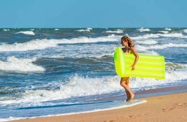 女性穿着泳衣的漂亮年轻女子手拿气垫在沙滩上奔跑沙滩热带户外