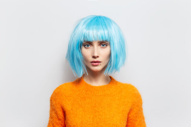 肖像摄影棚白衣映衬下的美丽少女肖像背景穿着橙色毛衣和蓝色假发时尚年轻现代