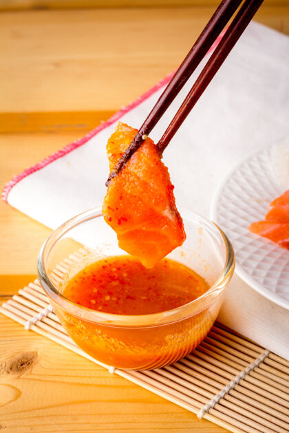 文化用木筷从海鲜酱碗里捞起的新鲜三文鱼蘸握融合
