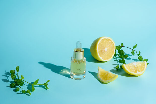 产品脸上的精华液用柑橘类水果柠檬和维生素c装在一个玻璃瓶中 用移液管在蓝色的背景上 这是家里自我护理皮肤的概念维生素面部有机