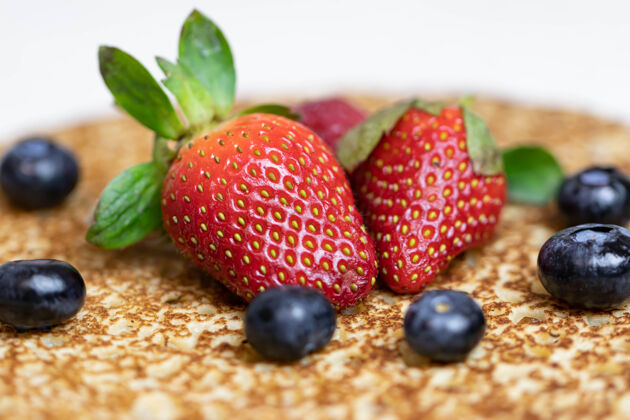 夏季成熟多汁的草莓和蓝莓躺在美味的煎饼上俄罗斯料理国家菜 带新鲜浆果团体蓝莓薄饼