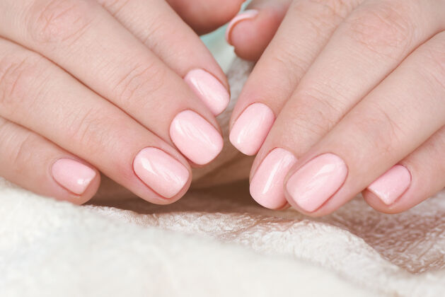 手指美丽的美甲和柔软的粉红色指甲油的女性手美甲女性角质层