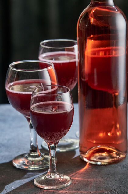 饮料石头桌上放着一瓶三杯的粉红色葡萄酒酒杯玫瑰庆典