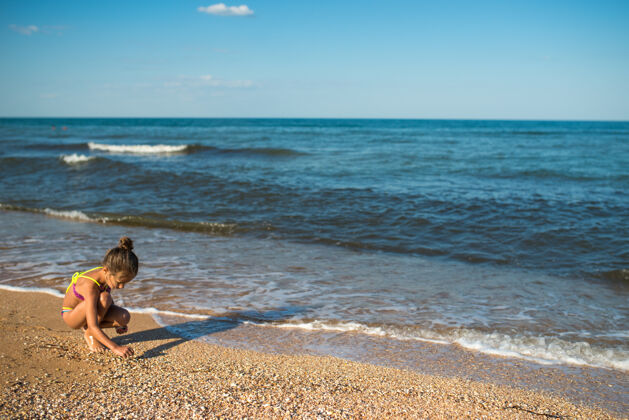 孩子孤独的小女孩坐在大海的背景下 在沙滩上写着什么自然年轻收藏