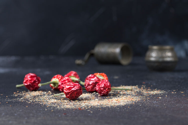开放深色背景上的干辣椒和天然香料散落在地板上表1.1在黑色背景上打开胡椒罐配料串干燥