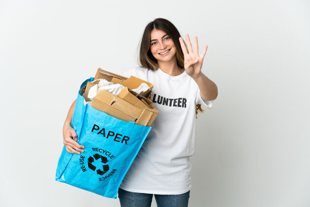 志愿者年轻女子拿着一个装满废纸的回收袋 在白色的纸上快乐地数着四根手指年轻数字垃圾