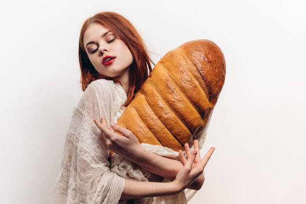 射击美丽的女人抱着面包用她的手化妆透明织物在她的肩膀上健康选择美女