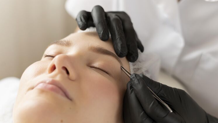 沙龙在美容院修眉毛的年轻女人拔治疗面部
