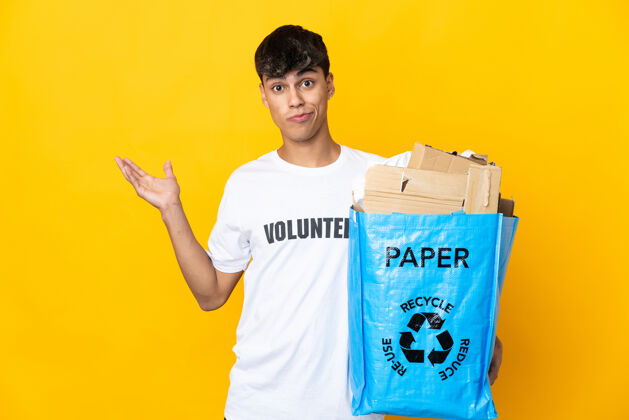 再利用一名男子举着一个装满废纸的回收袋翻越隔离的黄墙 一边举手一边表示怀疑垃圾环境浪费
