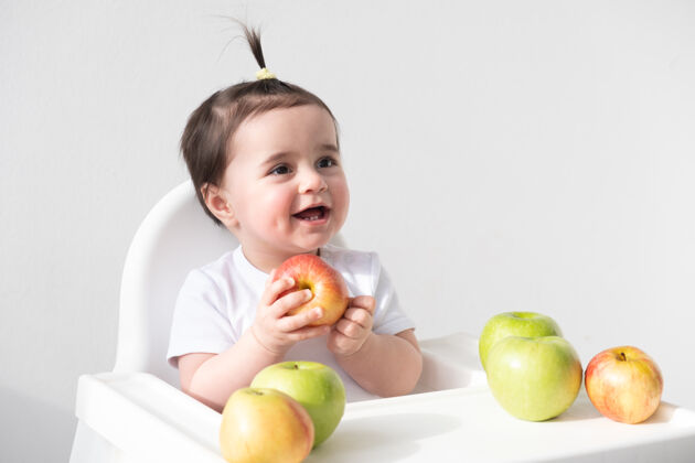 幼儿坐在婴儿椅上吃白苹果的女婴苹果早餐饥饿