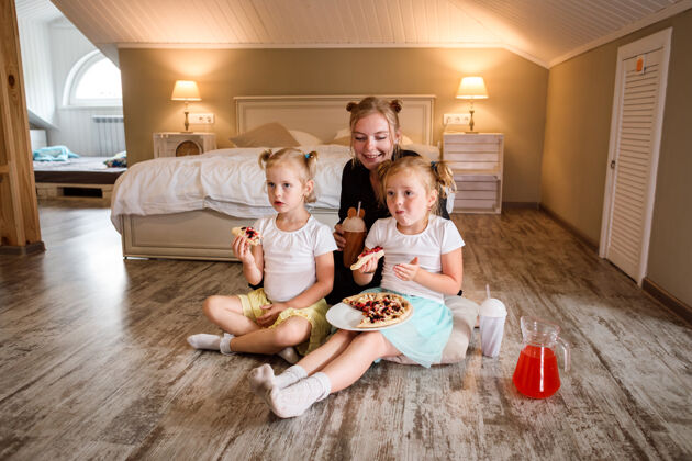 女儿妈妈和她的两个女儿看电视 吃比萨饼 喝果汁饮料电影房子