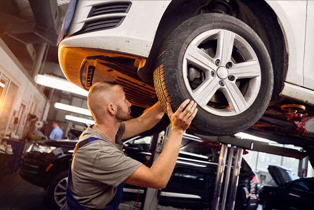 主控英俊的汽车修理工安装和检查车轮的汽车汽车检查发动机