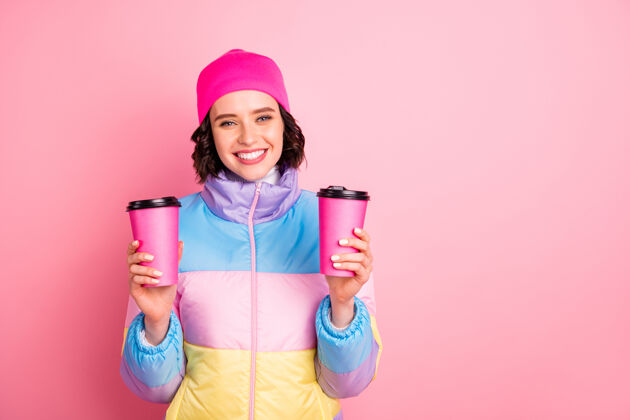 季节她的肖像她漂亮迷人可爱开朗活泼的女孩手里拿着两杯外卖绿茶隔离在粉红色的背景美丽纸