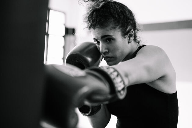 决心黑白肖像的女子拳击手训练拳击手套在健身房活力强壮拳击手