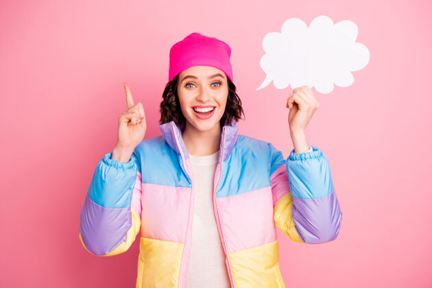 帽子照片中的神奇女士手里拿着空纸单 穿着暖色外套 背景是粉色的云闪亮外套