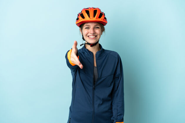 交易年轻的骑自行车的女子孤立在蓝色背景握手成交好合同骑车欢迎