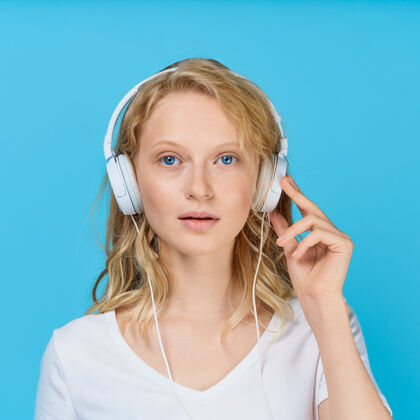 女孩特写肖像的年轻女子通过耳机听音乐的颜色明亮的蓝色调女人年轻听