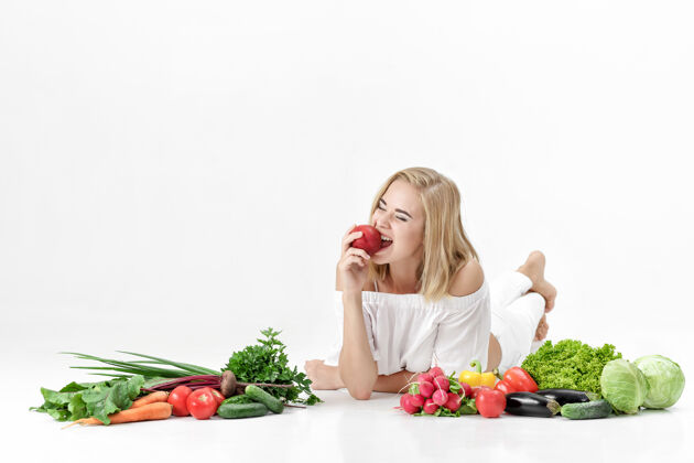 营养漂亮的金发女人 穿着白衣服 白色的桌子上放着很多新鲜蔬菜背景女孩她在吃油桃生活方式一个背景