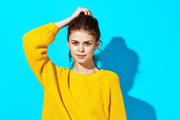 手势穿黄色毛衣的女人时尚发型休闲装不规则剪裁的风景蓝墙诚实成人女性