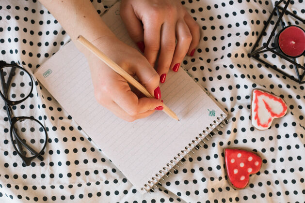 铅笔女人的手与完美的指甲握铅笔和螺旋记事本蜡烛笔记本页面