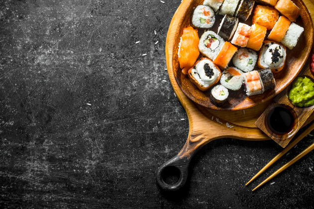 鳄梨新鲜的寿司卷放在盘子里 放在砧板上 用筷子和酱汁卷传统美食