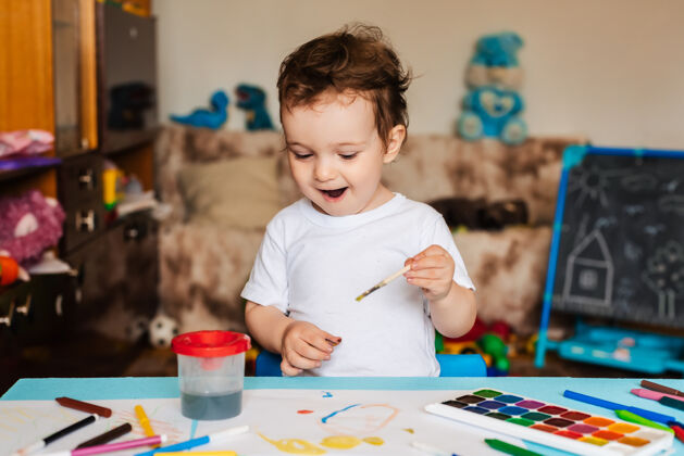 可爱快乐快乐的孩子用画笔在纸上用五颜六色的颜料画画艺术孩子色彩
