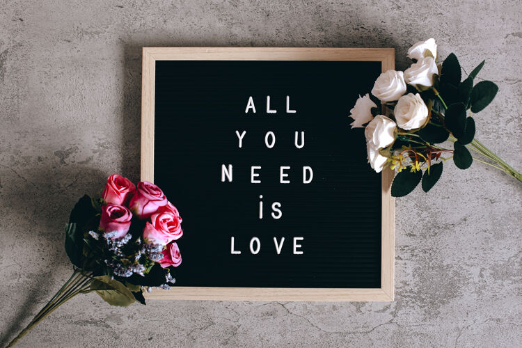 浪漫信笺上写着“你所需要的就是爱”和五颜六色的玫瑰花心木材黑板