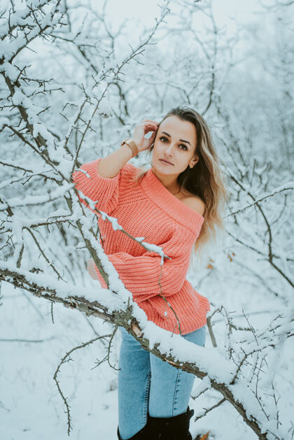 寒冷一个穿着粉色宽松毛衣和牛仔裤的漂亮女孩在寒冷的雪域森林里快乐快乐享受