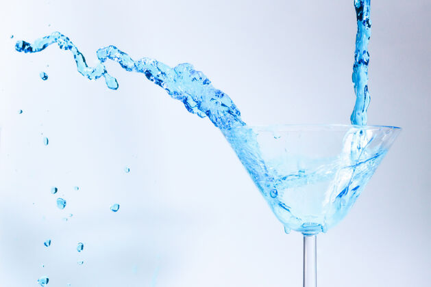 冷蓝色液体鸡尾酒玻璃玻璃蓝色的水里充满了飞溅的液体运动透明新鲜
