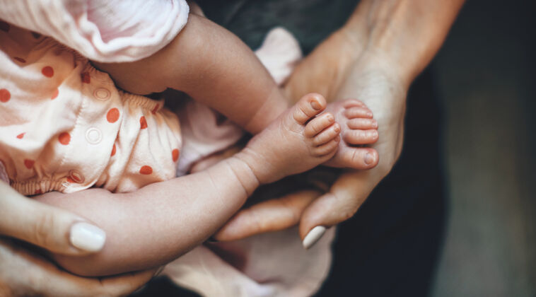 生命高加索母亲抱着女儿的腿在她的手掌里 同时拥抱她新抱按摩