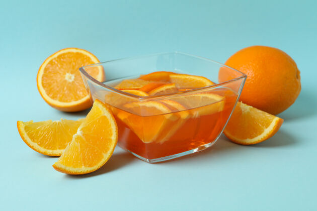 餐厅一碗橙色果冻 蓝色背景上有橙色切片吃明胶果酱