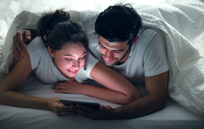 女性在床上看一些平板电脑上的东西 在卧室里放松伴侣浪漫冲浪