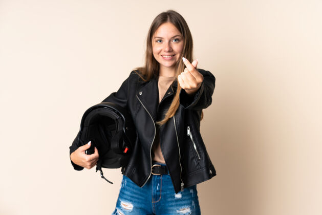 年轻立陶宛年轻女子手持摩托车头盔 在米色背景下做着手势呼叫表情摩托车
