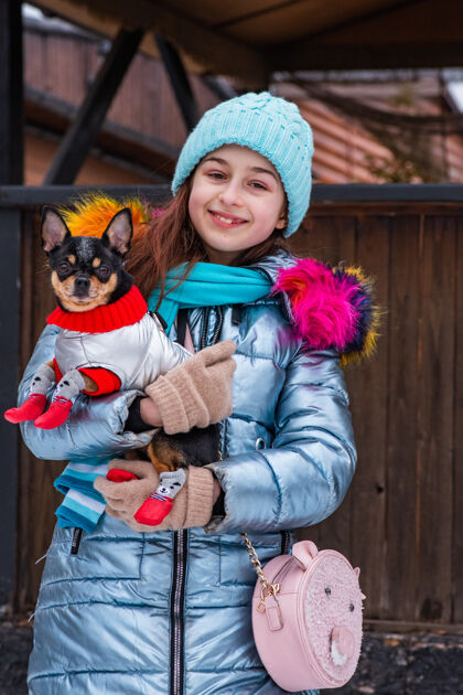 肖像女孩和狗温特女孩蓝色的夹克.狗在衣服青少年抱着宠物微笑狗年轻人