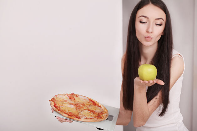 特写拿着苹果 鱼鳞和披萨的女人食物饮食切片