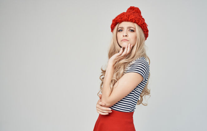 女性一个戴着红帽子 穿着条纹t恤 站在灰色墙上的肥皂女人 金发碧眼青少年针织女人