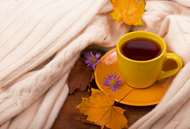 棕色一杯热茶和秋叶 在棕色的背景上杯子生活水果