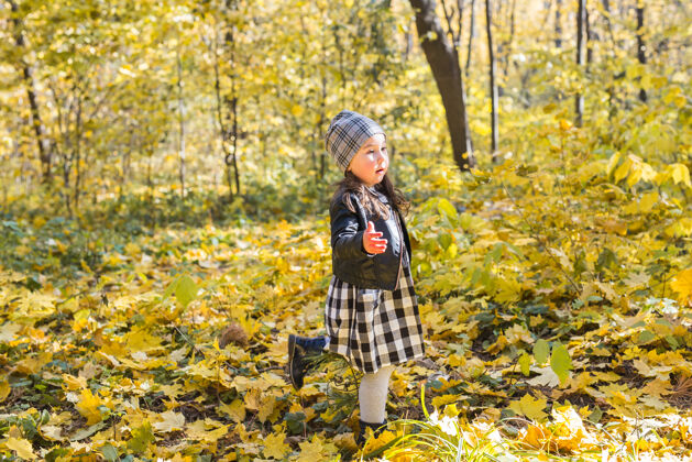 姿势快乐的小女孩在秋天的公园里散步秋天幼儿女孩