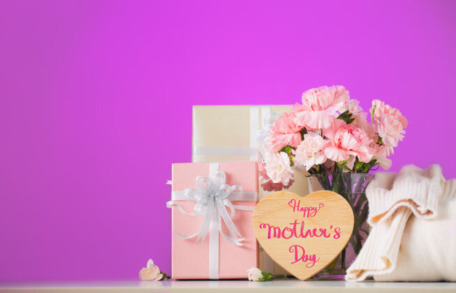 墙静物与甜蜜的康乃馨花和礼物放在桌上 母亲节的概念盒子康乃馨桌子