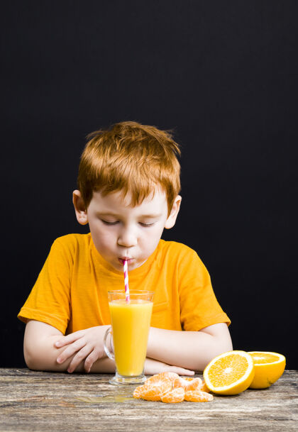 素食者一个非常漂亮的红发男孩 用柑橘类水果葡萄柚做果汁男性杯子漂亮