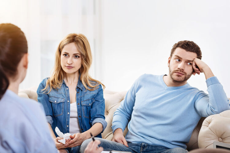 心理存在无聊愉快有胡子的好男人坐在他妻子旁边 看着别处 却不愿意参与讨论心理治疗支持妻子