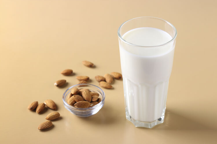 复制空间米色表面有新鲜杏仁牛奶和杏仁的玻璃杯 健康纯素牛奶替代品 水平格式 文本空间 特写玻璃蔬菜生物