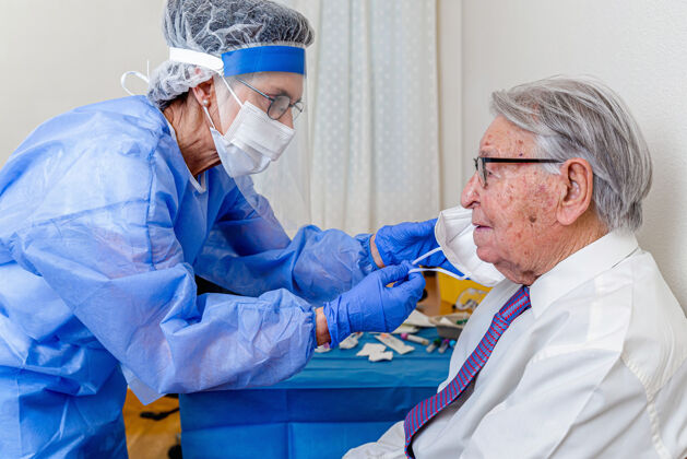 流行病穿冠状病毒防护服的护士摘下一位老人的面具小瓶检疫保护