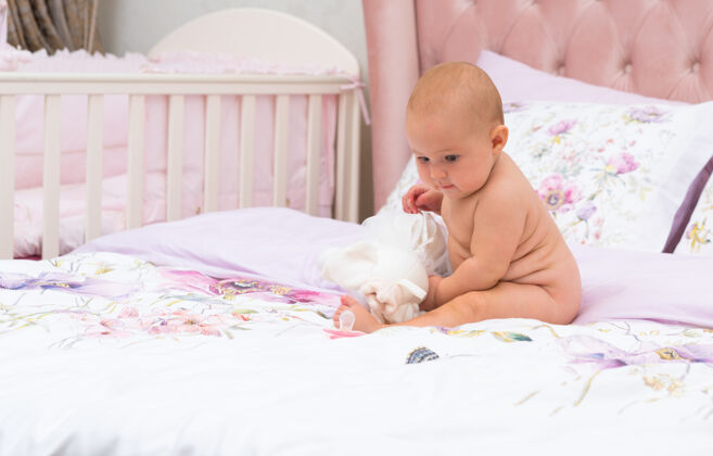 娃娃一脸严肃的小宝宝在床上玩玩具 没穿衣服 在父母的卧室里用拷贝空间全拍复制空间温柔可爱