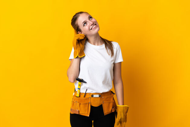 怀疑年轻的电工女人孤立在黄色的背景下思考一个想法车间年轻手工