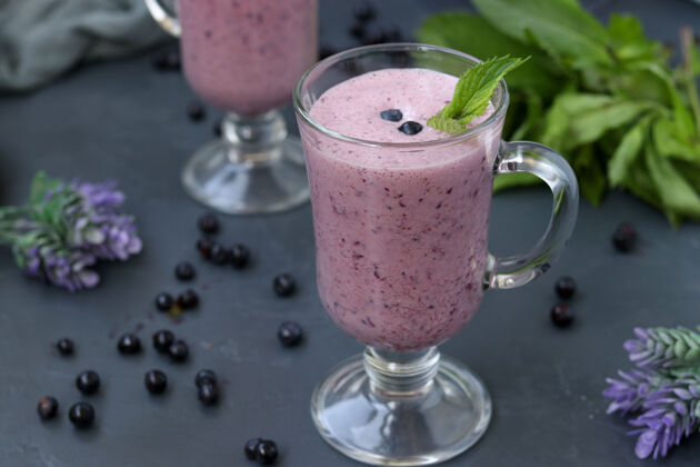 牛奶营养丰富的鸡尾酒配酸奶和蓝莓放在深色的玻璃杯里 健康饮食饮料奶昔营养