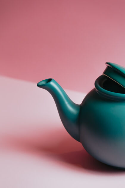 器皿一个简约的特写一个蓝色茶壶在粉彩粉红色的背景抽象稀疏阴影