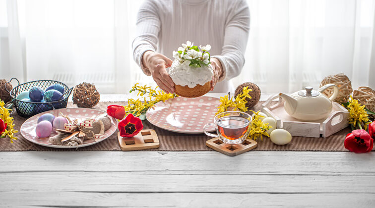 茶复活节作品中 女性手拿蛋糕 茶 花 蛋和装饰品详情.复活节家庭假日概念装饰花鸡蛋