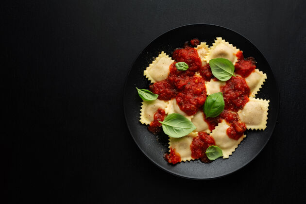 叉子美味的意大利馄饨配番茄酱和罗勒 放在深色盘子里方形午餐馅料