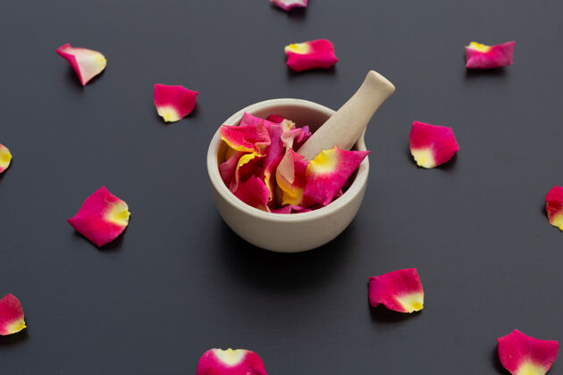 爱玫瑰花瓣在瓷臼里 用杵隔离在黑暗的表面上芳香明亮健康